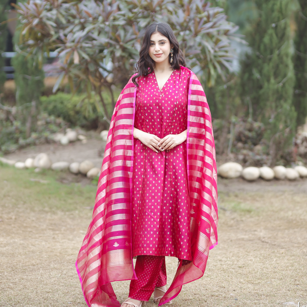 Front centered view of a woman wearing a pink handwoven Banarasi silk suit with gold and silver Sona Rupa motifs and a matching striped organza tissue dupatta.