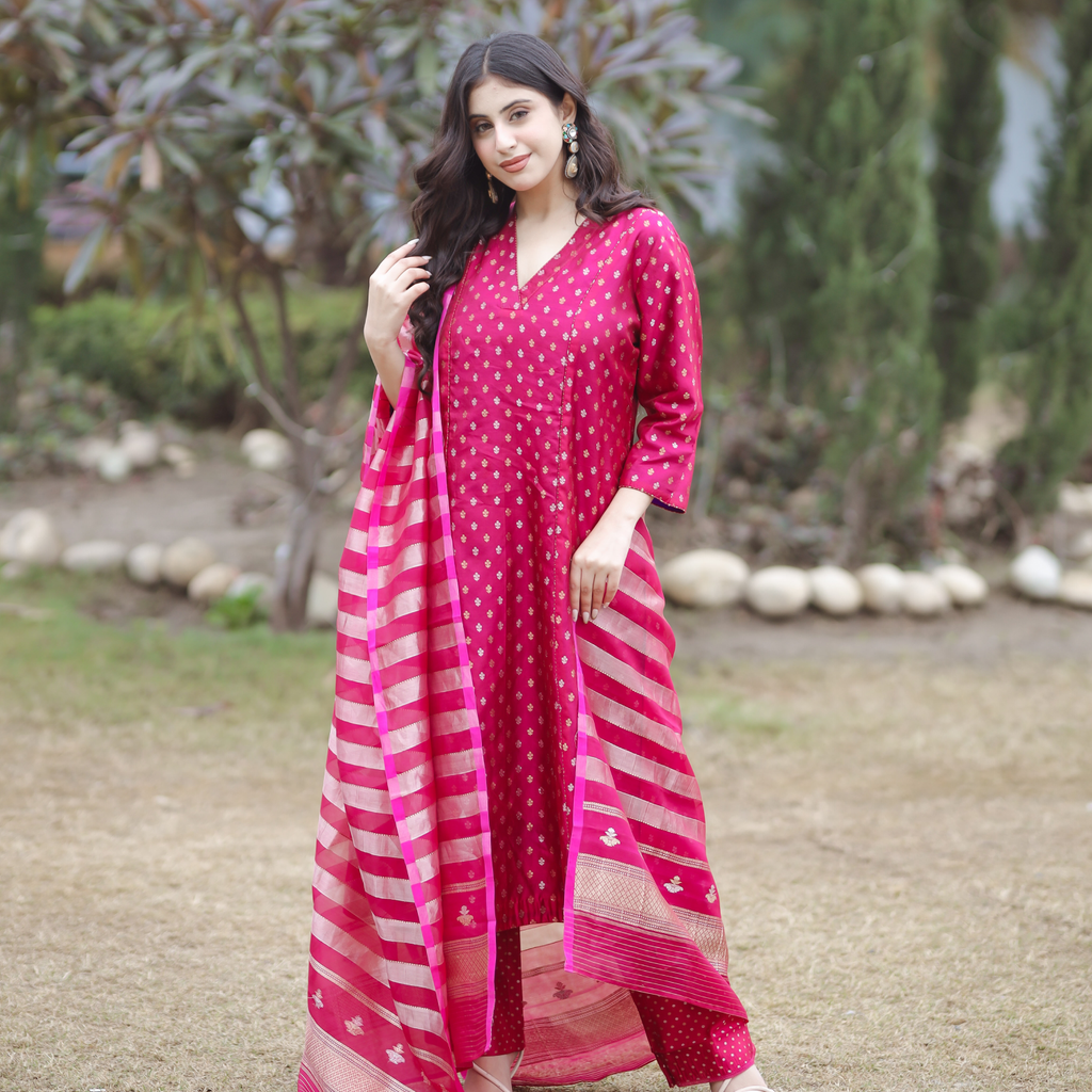 Full-length outdoor view of a pink Banarasi silk suit with gold and silver Sona Rupa motifs, showing the matching zari dot pants and striped organza dupatta.