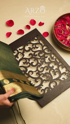 Elegant black Handwoven Pure Katan Silk Saree with a gold zari border and traditional check pattern, styled with red rose petals on a white background.