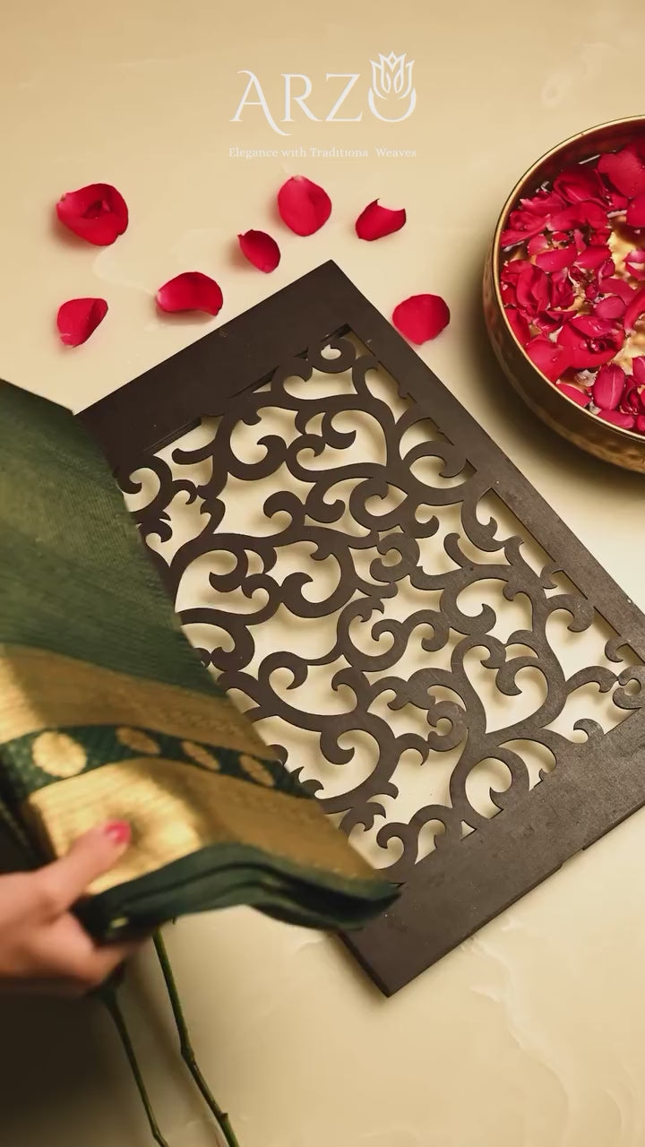 Elegant black Handwoven Pure Katan Silk Saree with a gold zari border and traditional check pattern, styled with red rose petals on a white background.