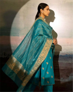 A model wearing a premium dark teal pure Banarasi silk suit with a matching Kora dupatta, featuring traditional intricate weaving.