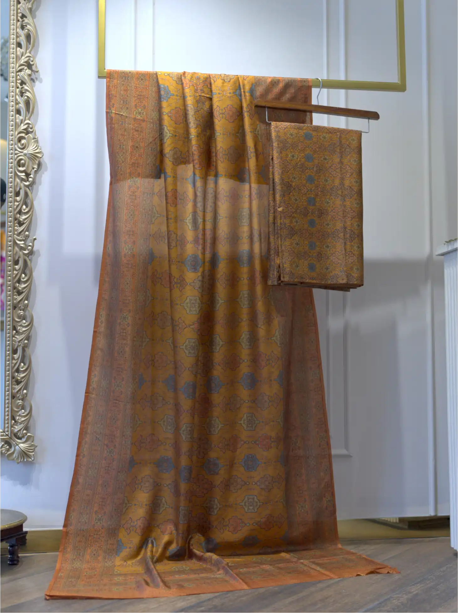 Unstitched Pure Boski Silk Mustard Yellow suit fabric draped on a display rack showing slate blue geometric print work and matching folded suit fabric
