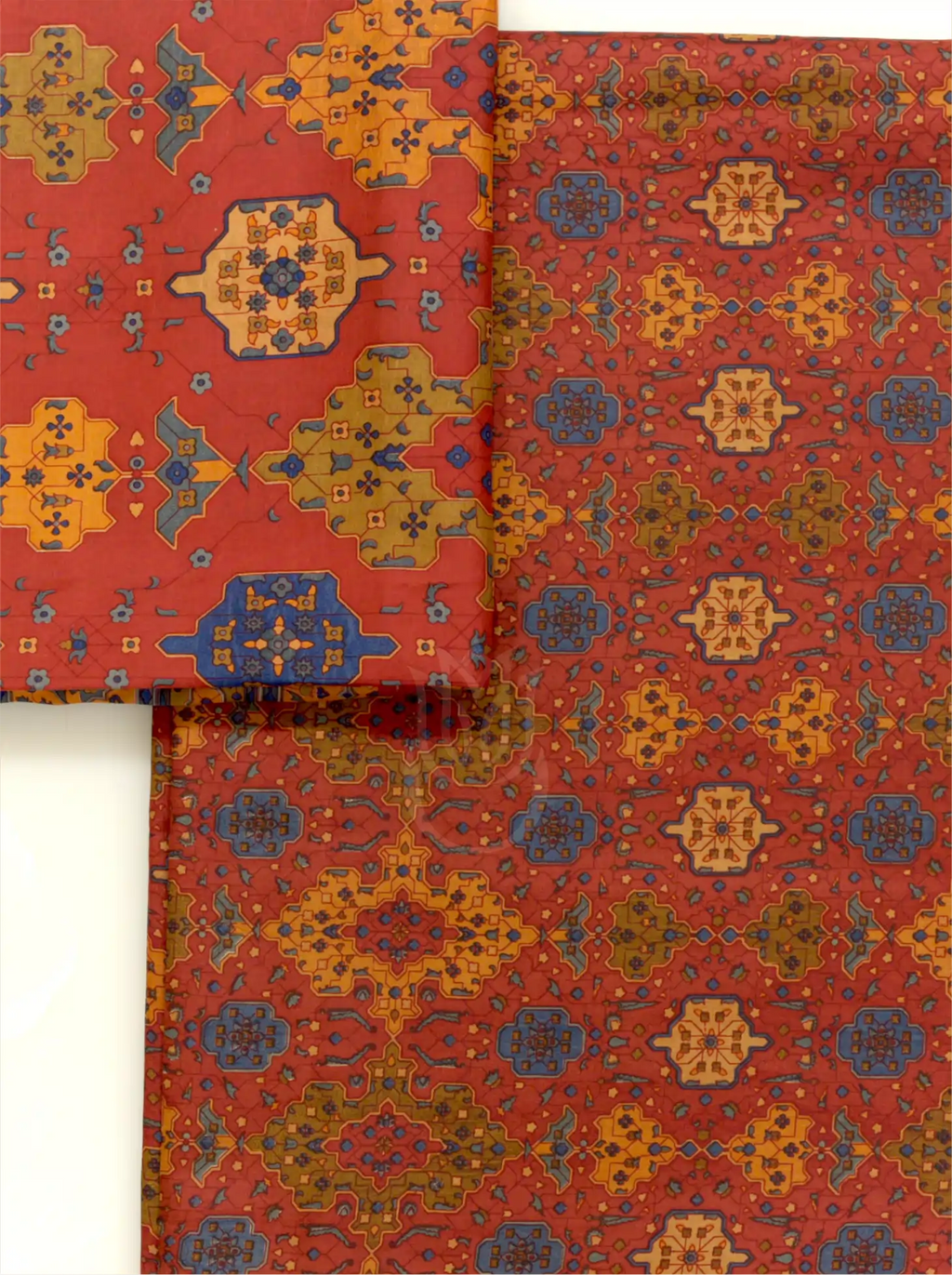 Folded rust red pure Boski silk fabric close-up showing detailed geometric and ethnic print pattern with mustard yellow and slate blue accents