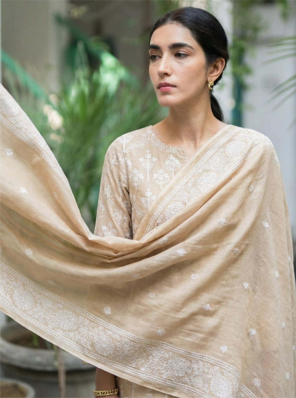 A woman modeling a premium beige Pure Chanderi cotton silk suit set featuring delicate white floral embroidery and a matching dupatta.