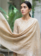 A woman modeling a premium beige Pure Chanderi cotton silk suit set featuring delicate white floral embroidery and a matching dupatta.