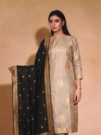 Woman wearing a beige Pure Kadwa Katan Silk suit with a black and gold dupatta.