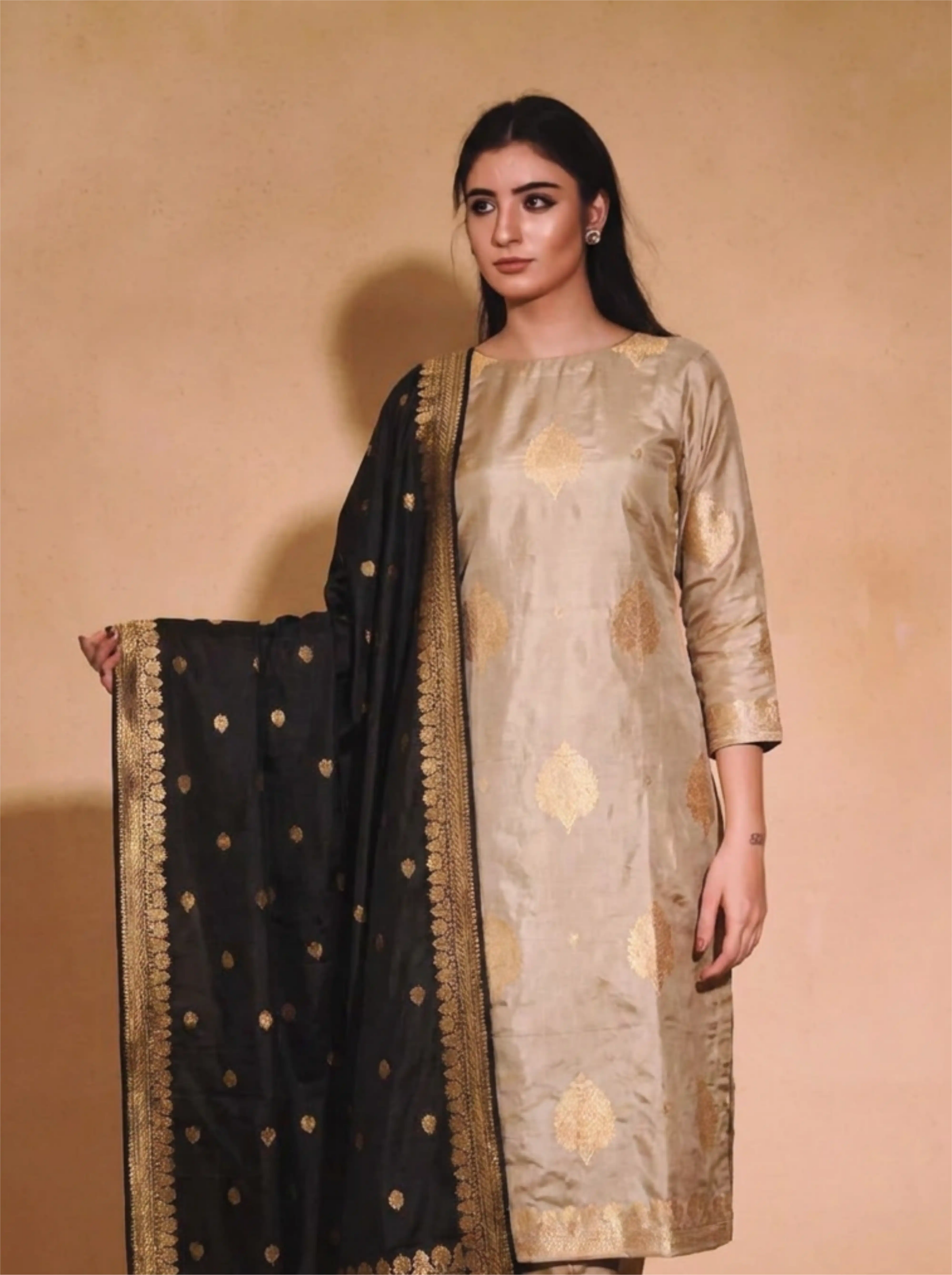 Woman wearing a beige Pure Kadwa Katan Silk suit with a black and gold dupatta.