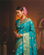 A woman wearing an elegant dark teal Pure Kanjivaram silk saree featuring rich gold zari weaving.