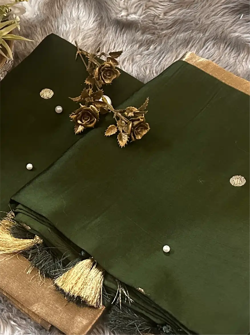 Unstitched green Pure Mango Silk Suit material featuring delicate circular motifs, a gold zari border with tassels, and decorative gold floral accents on a textured surface.