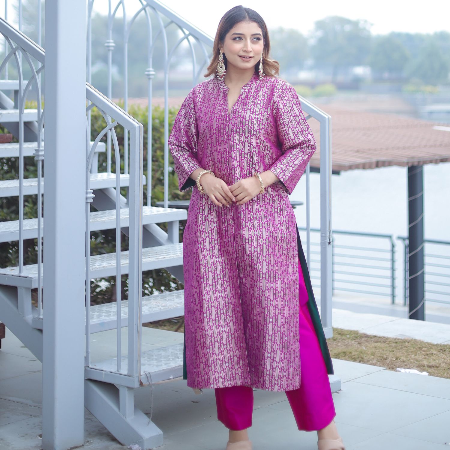 Model posing in a Royal Purple Handwoven Brocade Achkan suit, highlighting the rich gold zari floral patterns and the elegant fall of the long silk tunic.