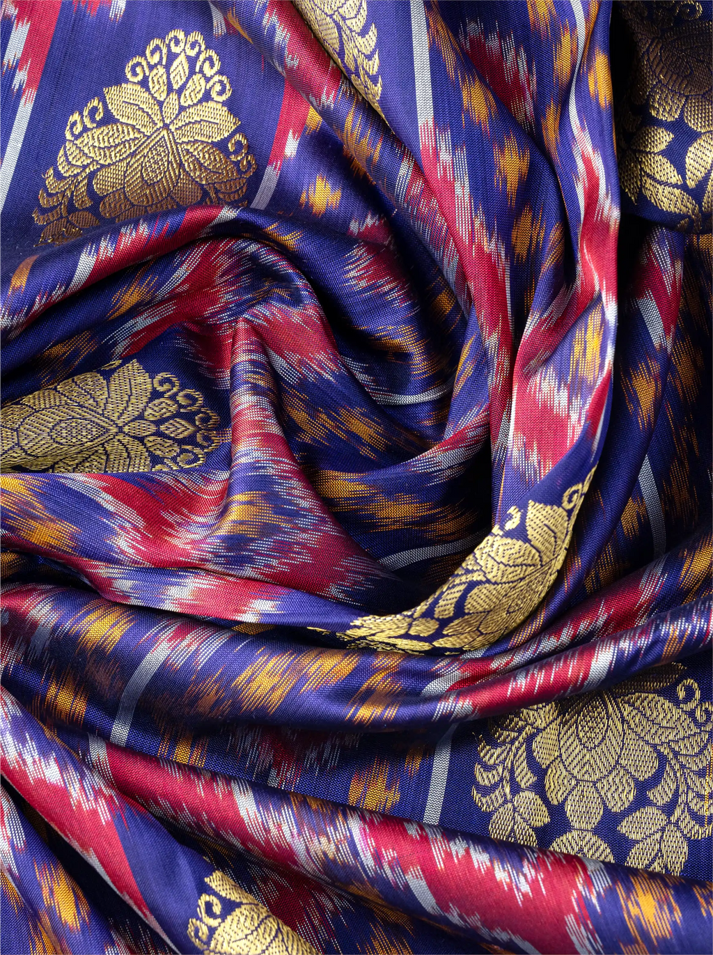 Macro shot of handwoven purple Patola silk saree showing a prominent metallic gold zari floral brocade motif over colorful ikat patterns.