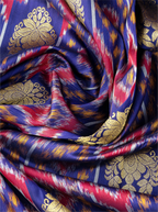 Macro shot of handwoven purple Patola silk saree showing a prominent metallic gold zari floral brocade motif over colorful ikat patterns.
