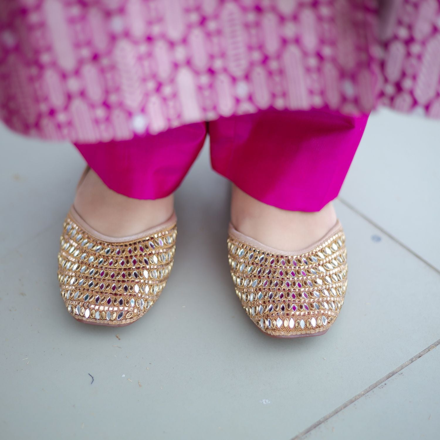Close-up of gold embellished juttis paired with royal purple silk pants, showcasing a complete festive styling look for the Handwoven Brocade Achkan suit.