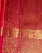 Close-up detail of a red silk saree featuring an intricate gold zari woven border and traditional paisley patterns.