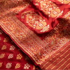 Close-up of the crimson red Nilambari Iktara silk suit highlighting the intricate gold zari floral border and handwoven bootas.