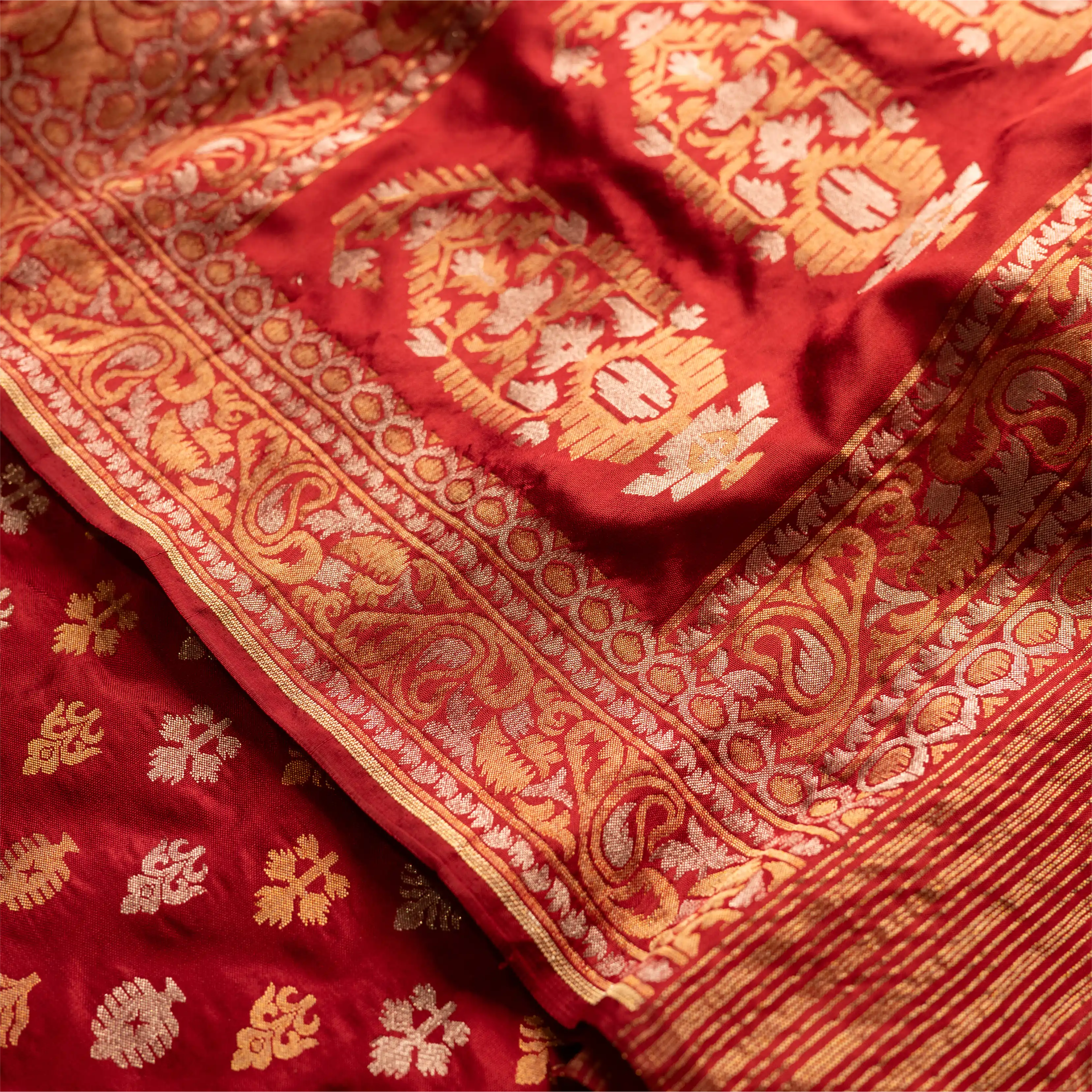Close-up of the crimson red Nilambari Iktara silk suit highlighting the intricate gold zari floral border and handwoven bootas.