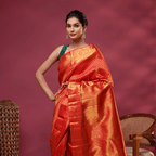 Close-up shot of the vibrant red and gold Kanjivaram silk fabric, highlighting the intricate traditional Resham embroidery and fine handloom weave texture.