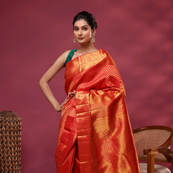 Close-up shot of the vibrant red and gold Kanjivaram silk fabric, highlighting the intricate traditional Resham embroidery and fine handloom weave texture.
