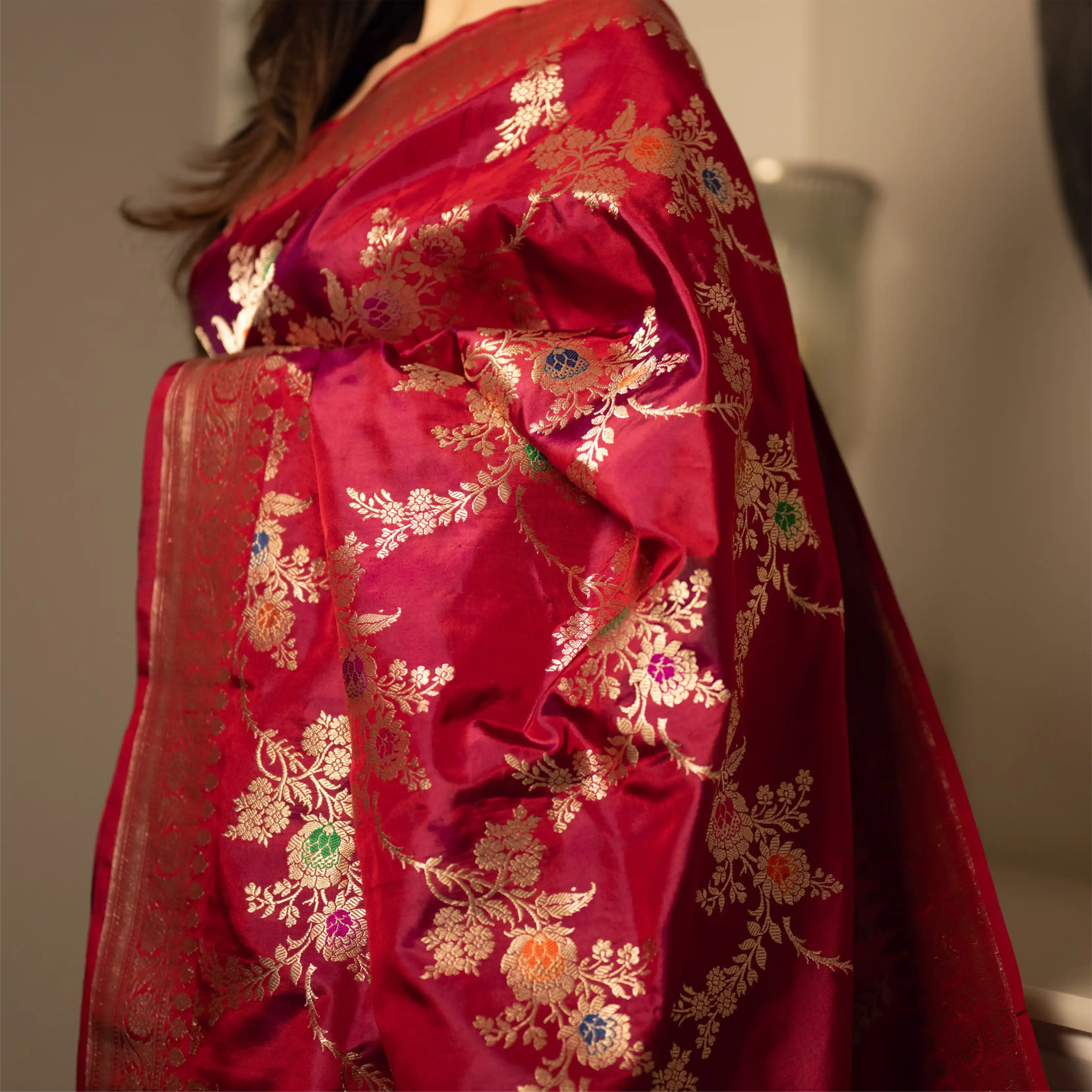 Side view of a premium Red Handwoven Katan Silk Saree highlighting the intricate gold zari pallu with colorful floral and paisley embroidery.