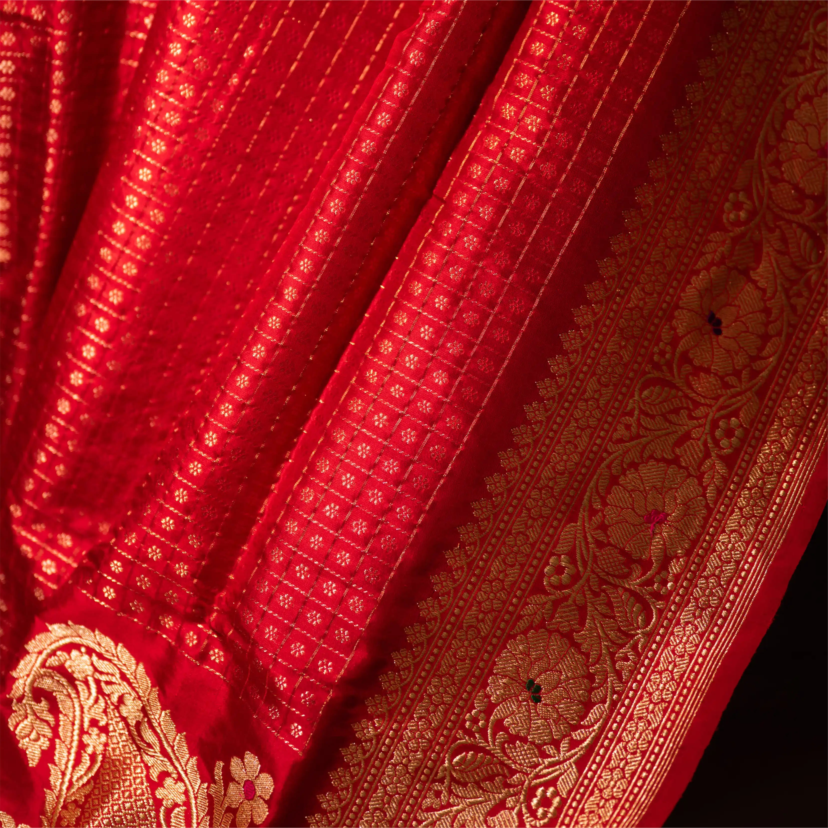 Detailed view of the handwoven gold zari motifs and rich crimson silk folds of a Red Organza Katan Silk Saree.
