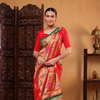 A model wearing the green and red Regal Harmony Paithani silk saree with intricate traditional handwoven motifs and a rich zari border, posing against an elegant backdrop.