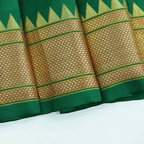 Close-up view of the unstitched green Paithani silk blouse piece fabric featuring a traditional gold zari temple border pattern.