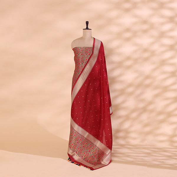 A mannequin displaying a luxurious deep red handwoven Banarasi silk suit set, featuring intricate gold zari floral motifs, fine craftsmanship, and an elegant traditional drape.