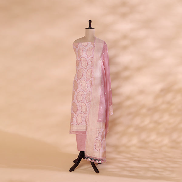 A handwoven Banarasi cotton silk Jamdani suit in soft blush pink featuring white Resham and Zari embroidery, displayed on a mannequin against a warm-toned backdrop.