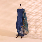 A royal blue Banarasi silk suit displayed on a mannequin, featuring intricate gold zari detailing and a vibrant floral Kalamkari patterned dupatta.