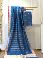 Handwoven royal blue Banarasi silk suit fabric with silver floral bootis draped on a hanger beside a gold zari striped dupatta featuring a contrast pink border.