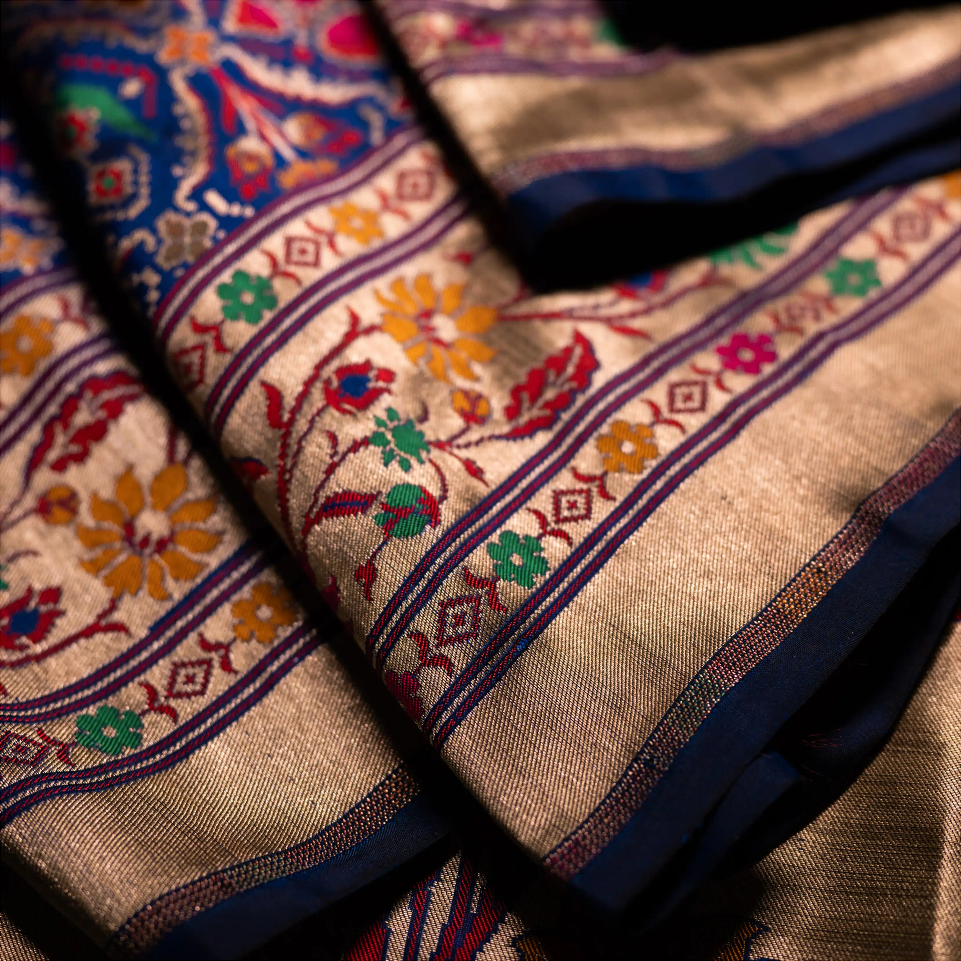Detailed view of a royal blue Paithani Patola silk saree showing the rich texture of the hand-loomed fabric and intricate gold zari border patterns