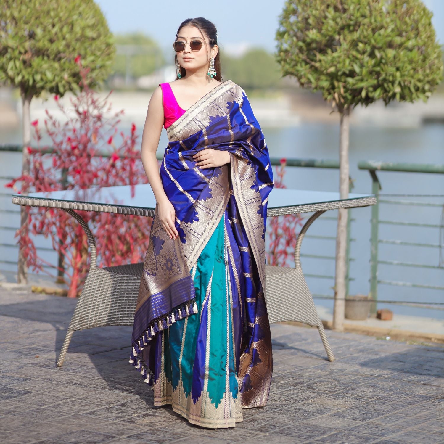 A model wearing a premium royal blue and teal Patola silk saree with traditional woven patterns, paired with a vibrant pink sleeveless blouse.