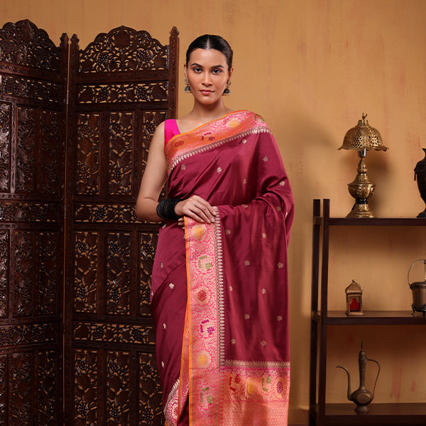 A model showcasing a royal orchid Katan silk saree featuring a detailed pink and orange sunset blush Paithani border, styled with a matching sleeveless blouse.
