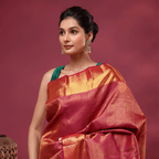 A model elegant in a royal plum Kanjivaram silk saree with intricate gold handwoven Resham work, styled with a contrasting sleeveless dark green blouse against a soft pink backdrop.