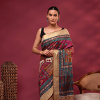 A model posing in the royal plum pure Tussar silk saree, showcasing the intricate multi-colour hand-embroidered Kantha floral patterns on the body and a classic gold border.