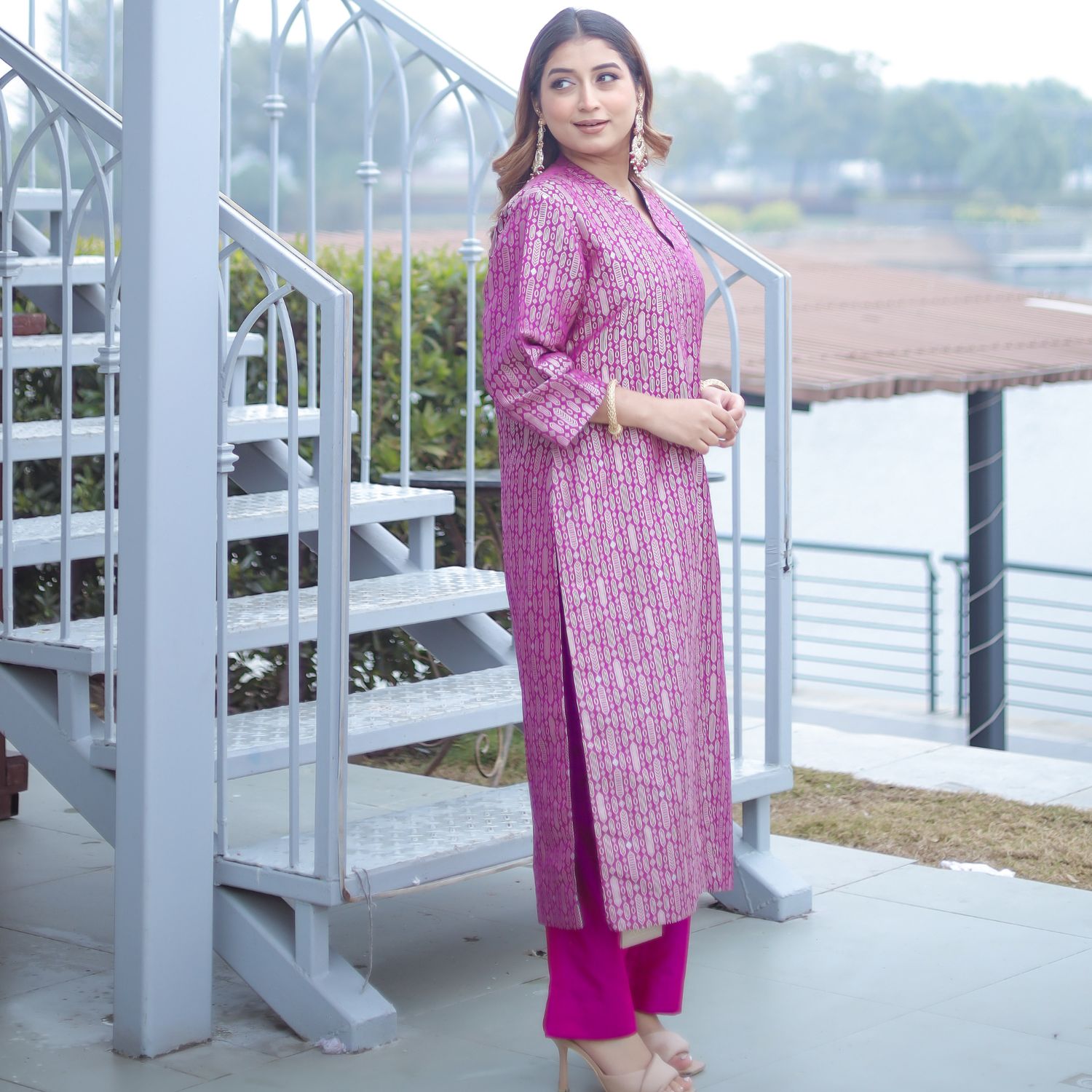 Full-length view of a woman in a royal purple handwoven brocade achkan with intricate gold patterns, matching purple silk pants, and an elegant side slit detail.