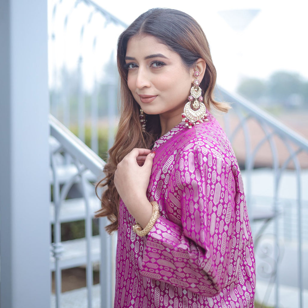 Elegant side profile of a woman in a royal purple handwoven brocade achkan, showcasing the rich texture of the silk fabric and intricate gold pattern details.
