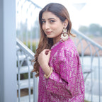 Elegant side profile of a woman in a royal purple handwoven brocade achkan, showcasing the rich texture of the silk fabric and intricate gold pattern details.