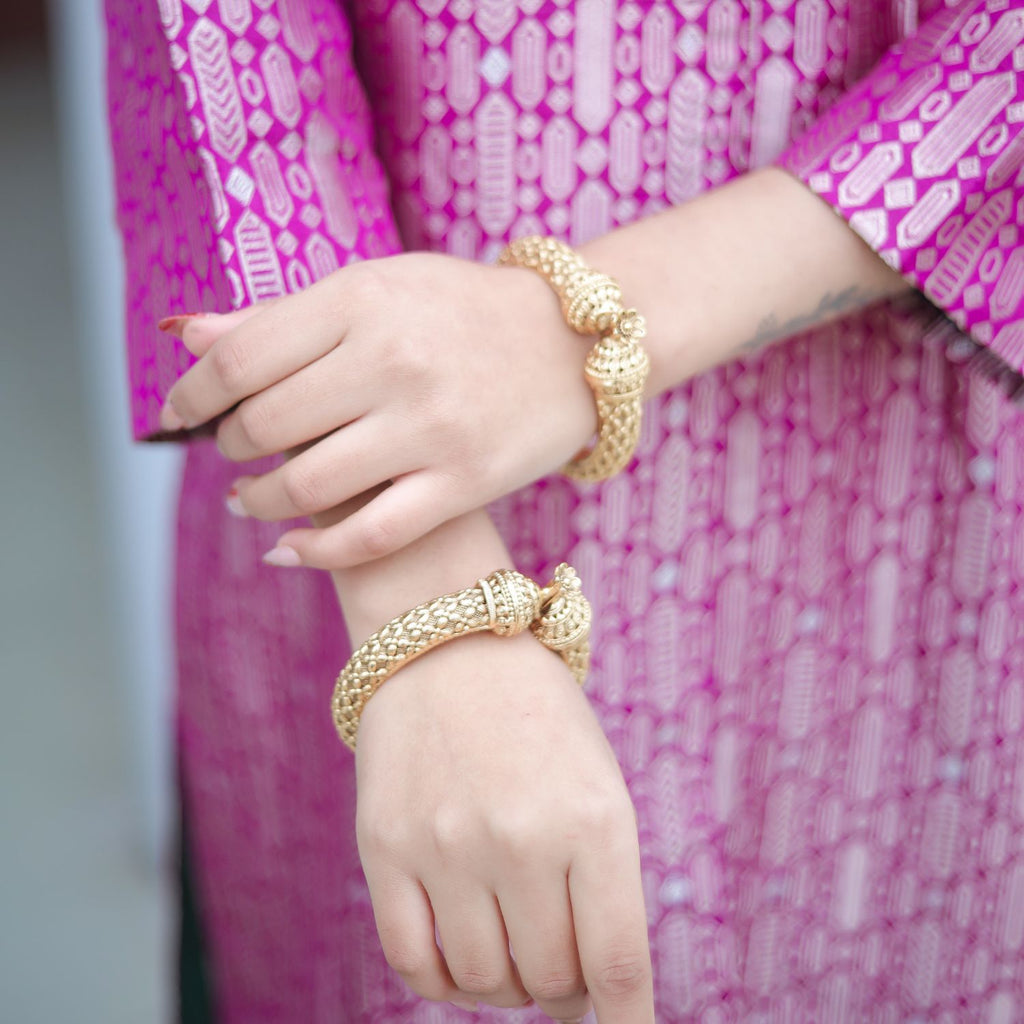 Close-up detail of the sleeve on a royal purple handwoven brocade silk achkan, showing the intricate gold zari weaving and premium fabric texture