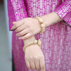 Close-up detail of the sleeve on a royal purple handwoven brocade silk achkan, showing the intricate gold zari weaving and premium fabric texture