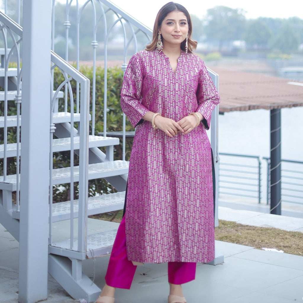 Woman wearing a royal purple handwoven brocade silk achkan with gold floral motifs, featuring a button-down front and contrast green silk lining.