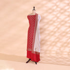 Rich ruby red pure crepe silk unstitched suit with intricate golden handloom work on the body, displayed on a mannequin with a soft cream mist dupatta.