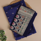 Close-up shot of the premium sapphire blue pure Banarasi silk dress material, highlighting the luxurious handloom fabric texture and intricate metallic zari bootis.