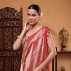 A model showcases the Scarlet Elegance Banarasi Silk Saree, featuring a regal red base draped beautifully with an intricate gold floral pattern and a contrasting heavy golden pallu.