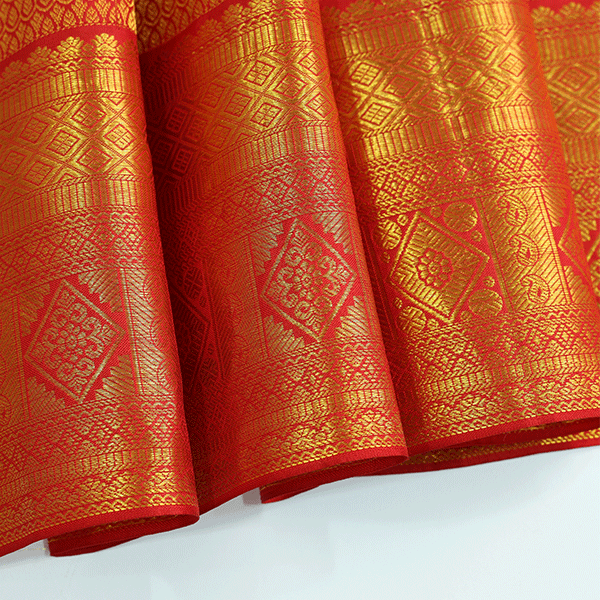 Flat lay presentation of the complete luxury Scarlet Gold Kanjivaram Silk Saree with its unstitched blouse piece, highlighting the authentic heritage craftsmanship.