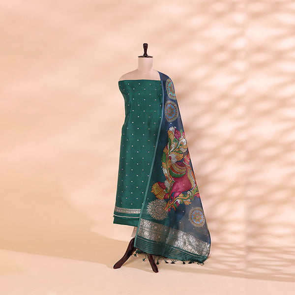 A sea green Banarasi Silk suit displayed on a mannequin, featuring intricate gold zari work, paired with a Kalamkari organza dupatta showcasing vibrant, multicolored floral prints.