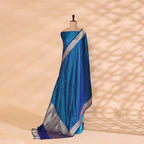 Flat lay presentation of the complete unstitched luxury suit set, showing the tranquil blue handwoven satin silk kurta fabric, matching bottom material, and silver border dupatta.
