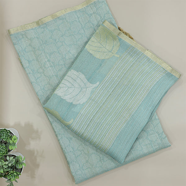 A flat-lay view of a light sky-blue handloom saree featuring elegant white leaf motifs and a subtle textured weave, perfectly displayed on a neutral background.