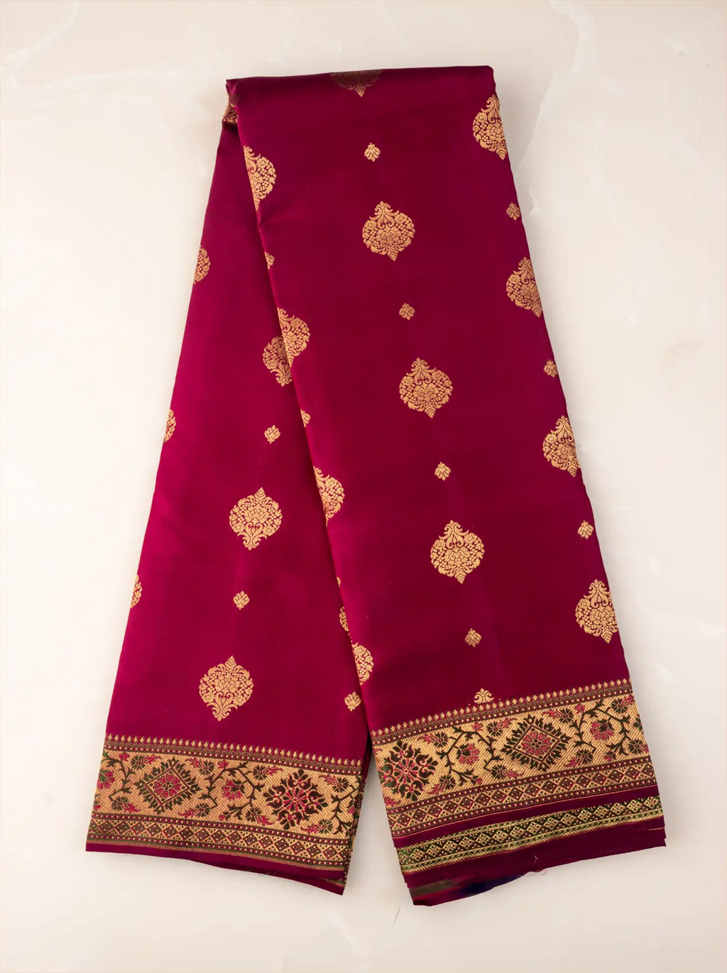 Folded handwoven Kanjivaram Paithani silk saree showcasing rich silk fabric, a wide gold zari border, and an elaborate pallu woven with intricate peacock and floral motifs in vibrant traditional colors.