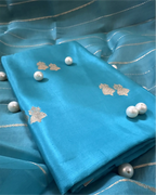 Close-up of premium turquoise blue pure Banarasi silk fabric featuring intricate gold zari motifs and pearl embellishments.
